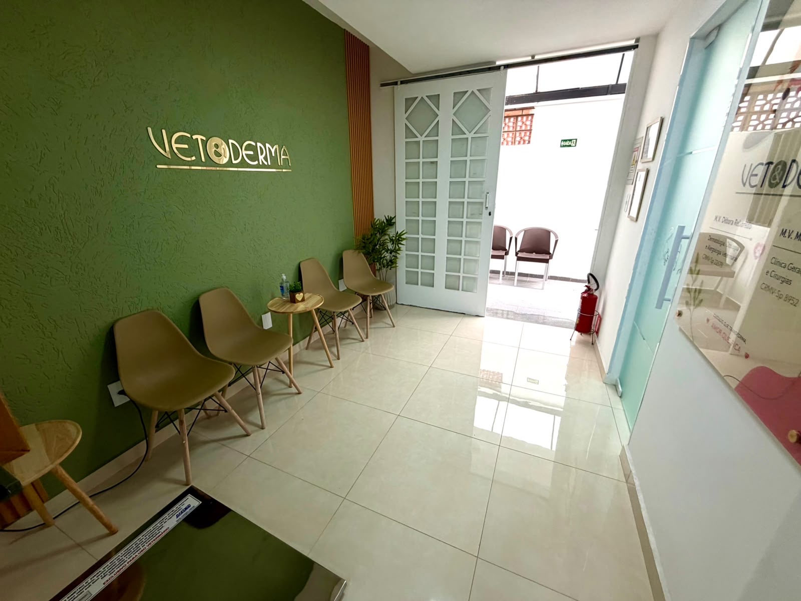 Consultório veterinário com mesa de exame, microscópio e espaço para conversar com os tutores